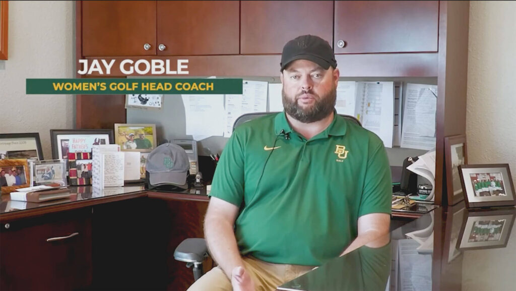 Jay Goble, women's golf coach, speaks directly into the camera while wearing a green polo and a hat